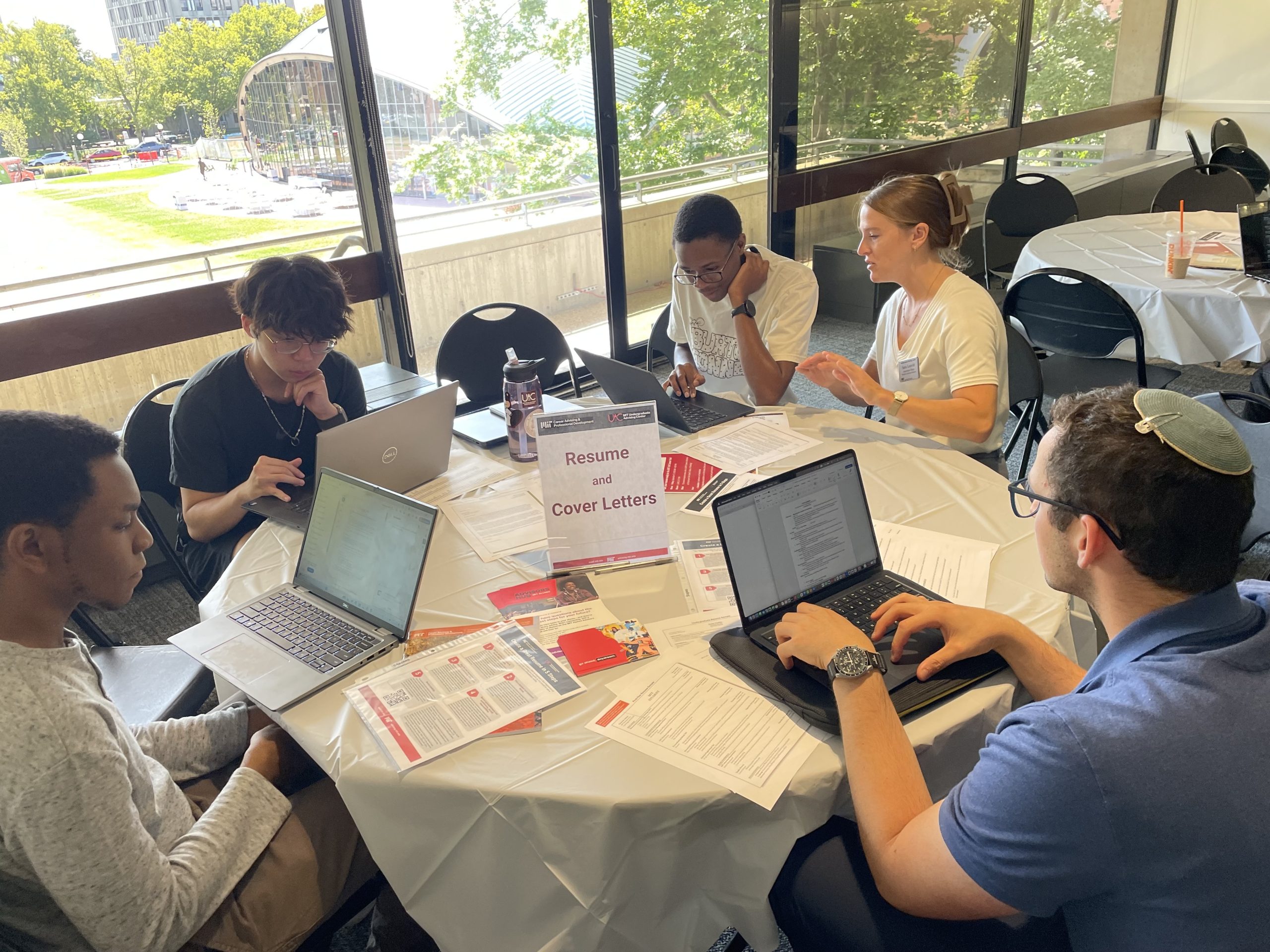 Students on laptops with an advisor