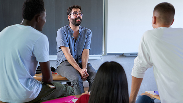 Alumn casually talking to students in a classroom